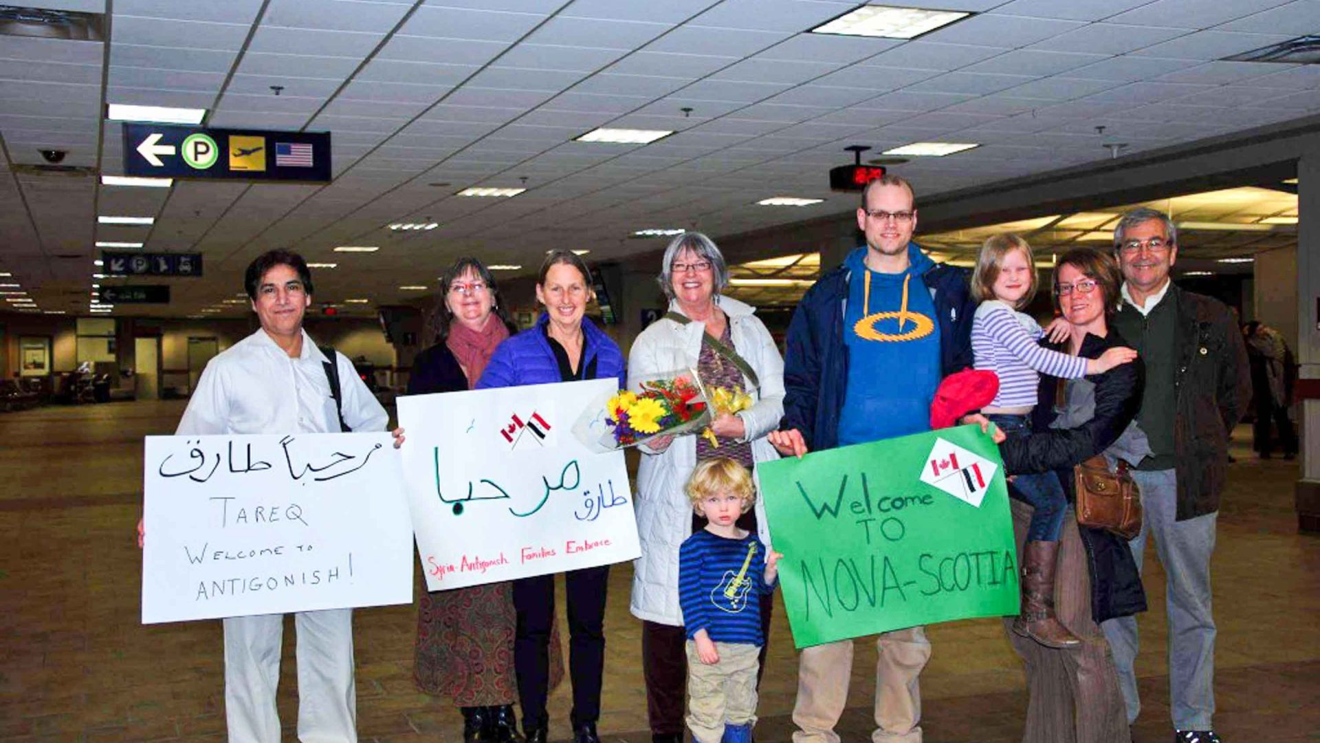 A crowd of people from the Antigonish community arrive at the airport to welcome Tareq to Nova Scotia with home made signs, some in Arabic.