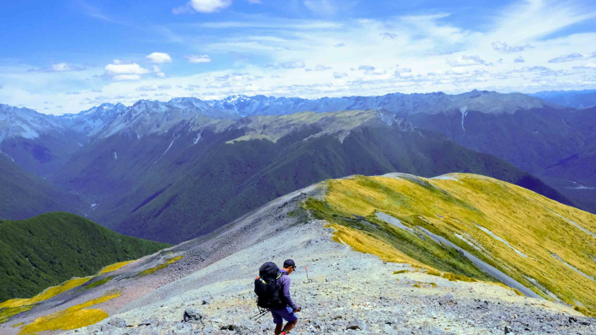 A person traverses down the ridge of a mountain.